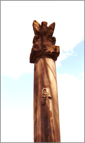 obelisk z piaskowca w kształcie kolumny, na której znajduje się orzeł oraz wyrzeźbiona szabla ułańska